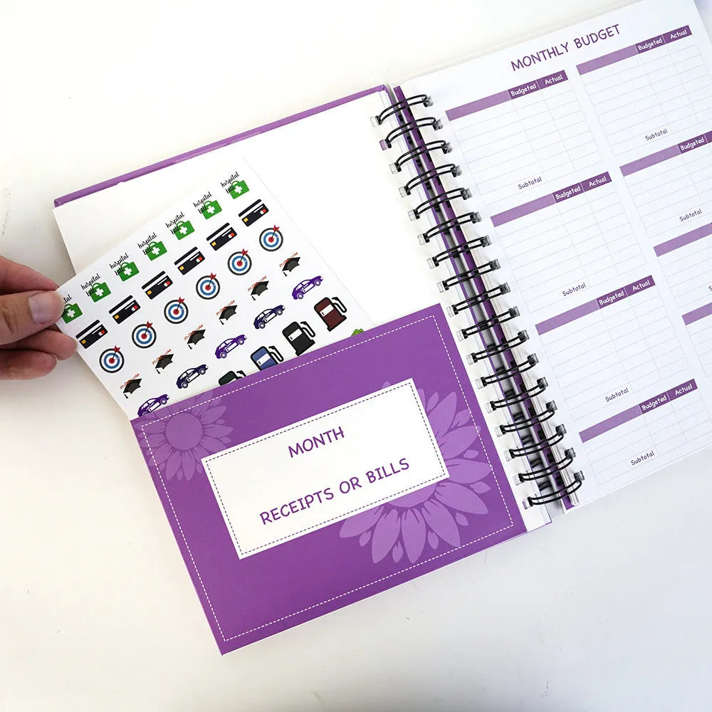 Purple coil-bound financial planning notebook with budgeting stickers and paper clips for monthly expense tracking