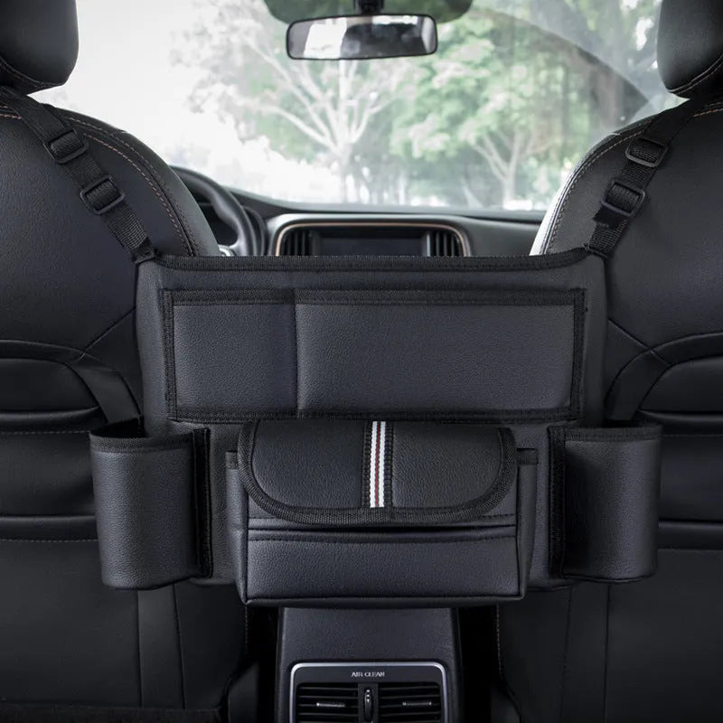 Black leather car interseat storage bag holding a tissue box, hanging between vehicle front seats.