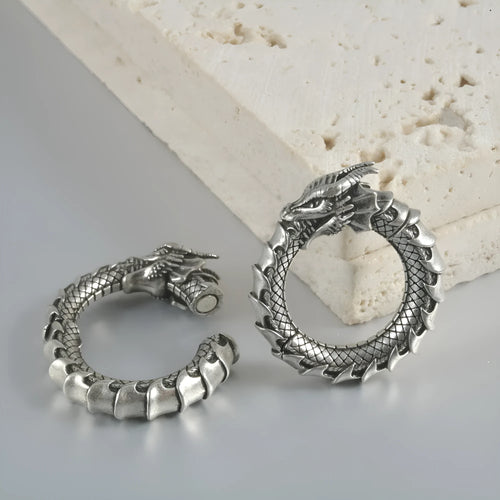 A pair of large antique silver alloy earrings featuring a hollow out geometric dragon design.