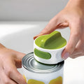 Compact manual can opener with stainless steel blade and ABS plastic body on a kitchen counter