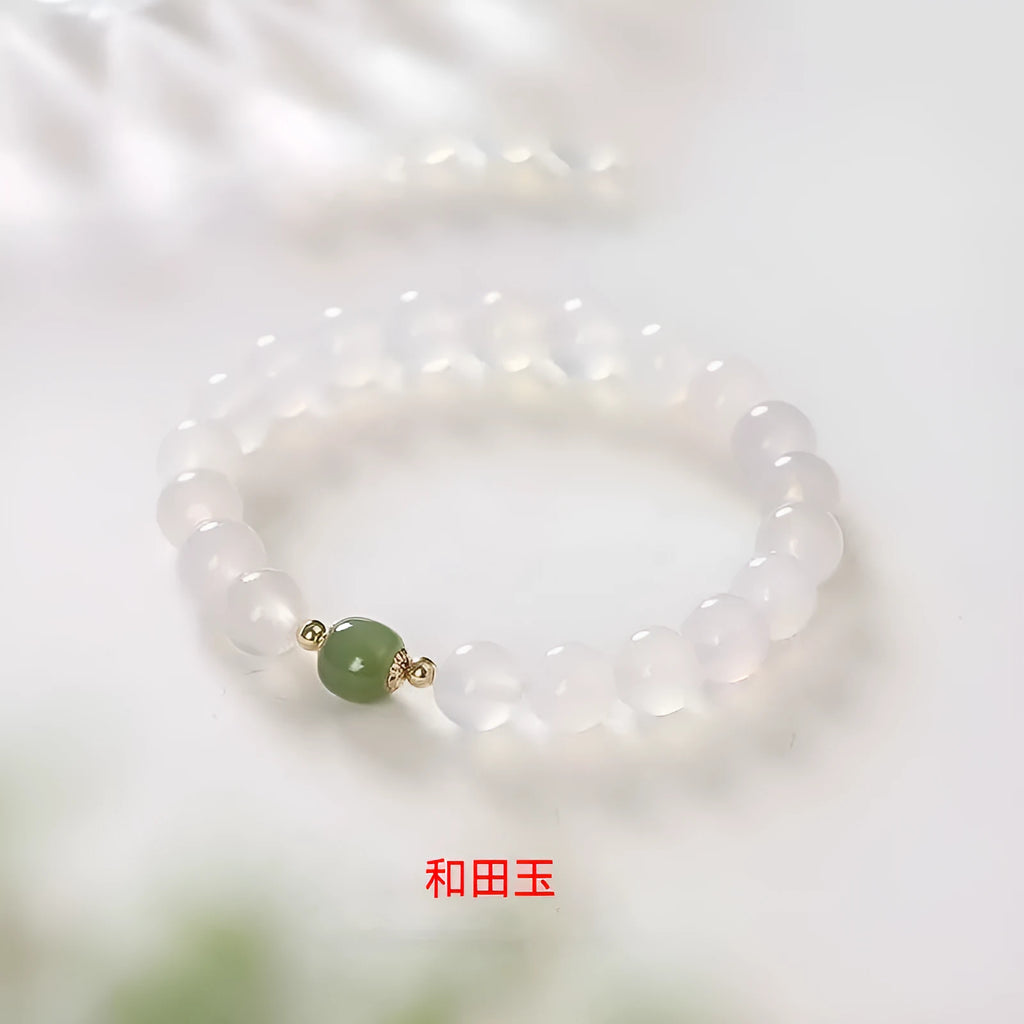 Handmade white agate and cinnabar bracelet with text design on a wrist.