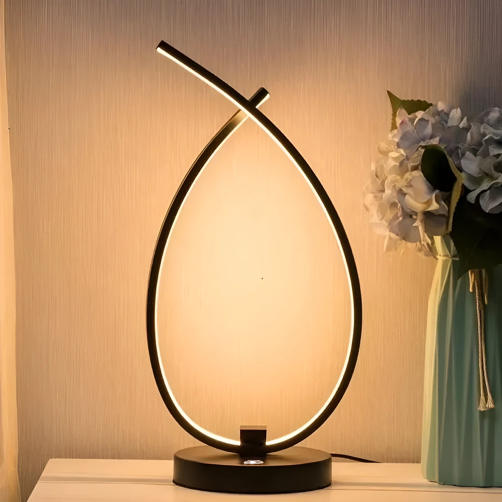 Black and white drop-shaped USB table lamp on a wooden desk.