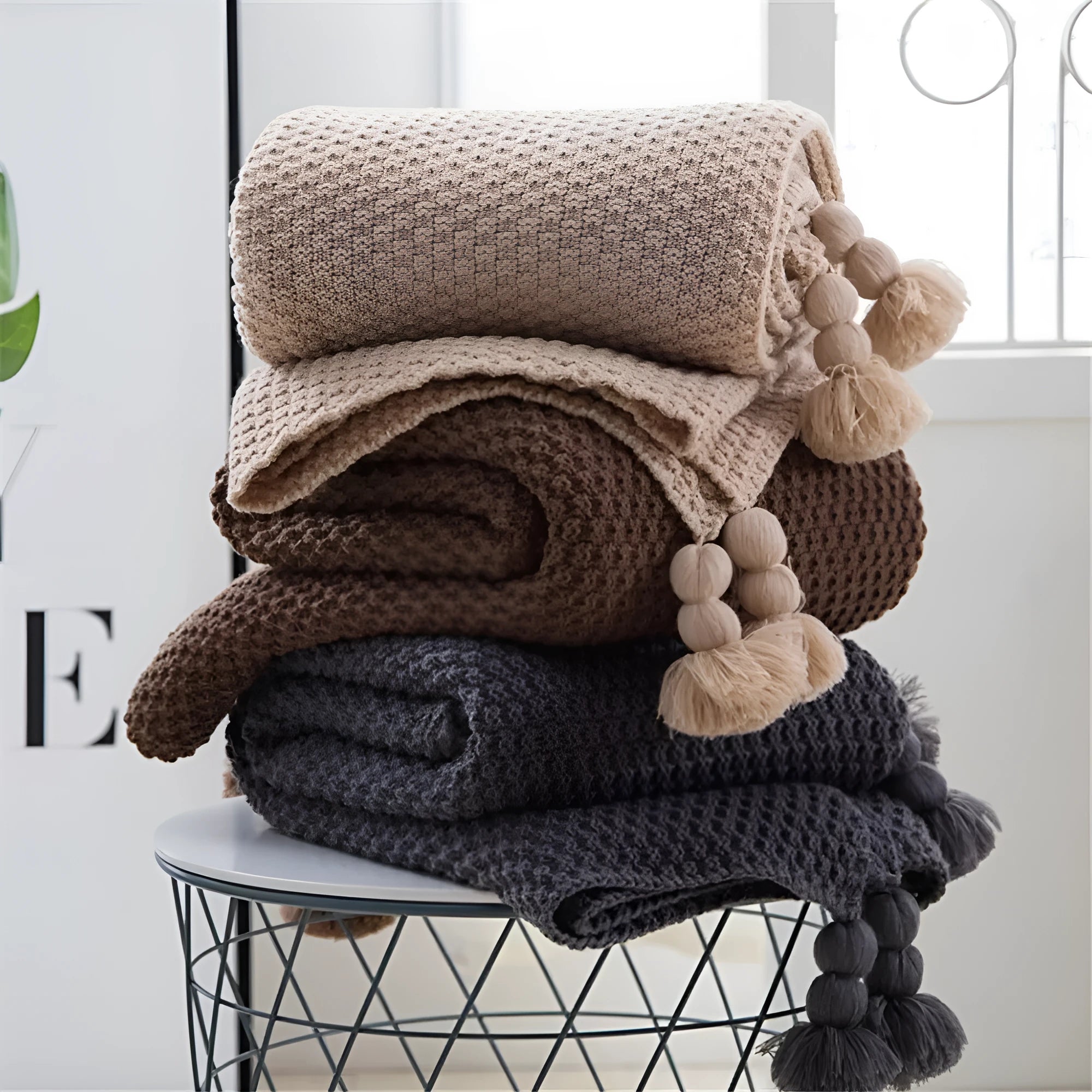 Fringed acrylic knit ball blanket 130x170cm in beige on a sofa
