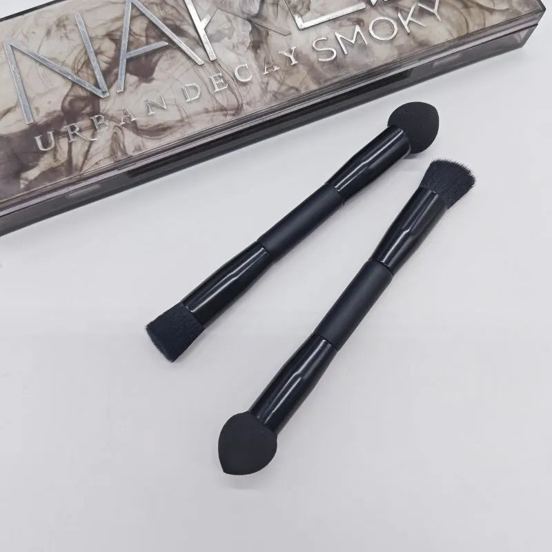 Double-headed black makeup brush with a pointed concealer brush on one end and an angled sponge on the other.
