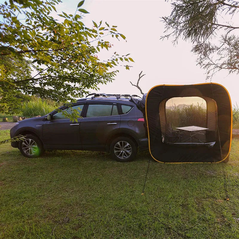 Black pop-up tailgate tent unfolded next to a car, showing its cubic 200cm shape and quick-throw design.