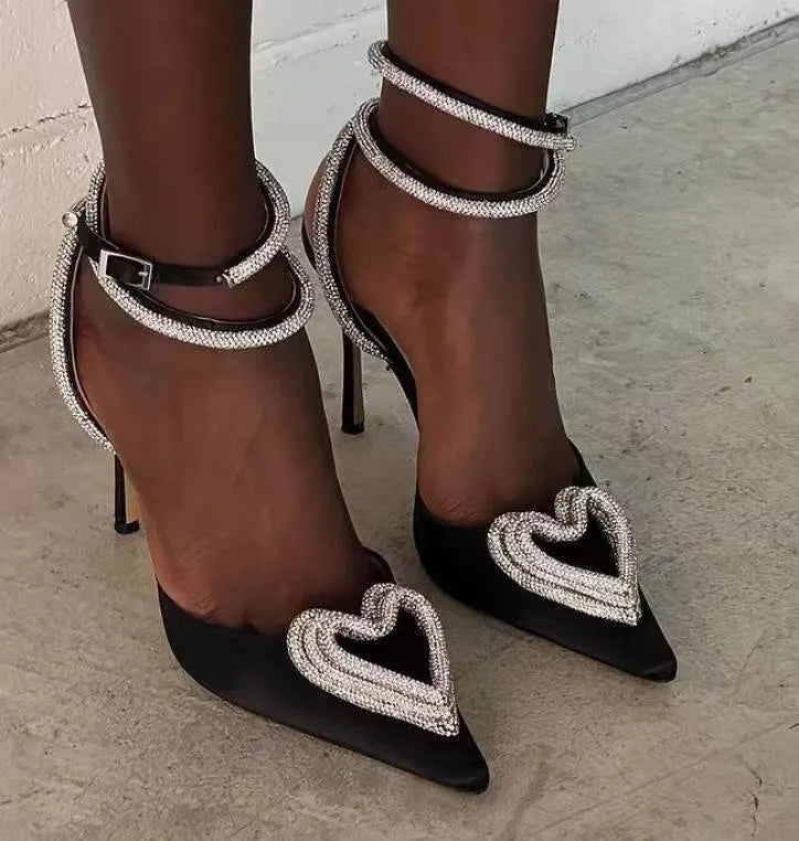 Women's pink satin sandal with heart-shaped rhinestone detail on pointed toe and adjustable ankle strap.