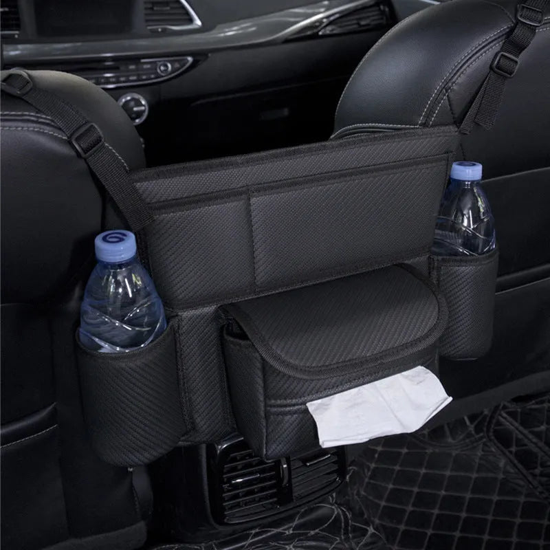 Black leather car interseat storage bag holding a tissue box, hanging between vehicle front seats.