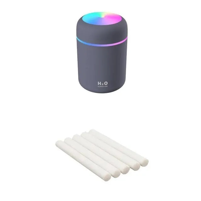 Pink USB desktop humidifier with LED lights and water tank on a wooden desk.