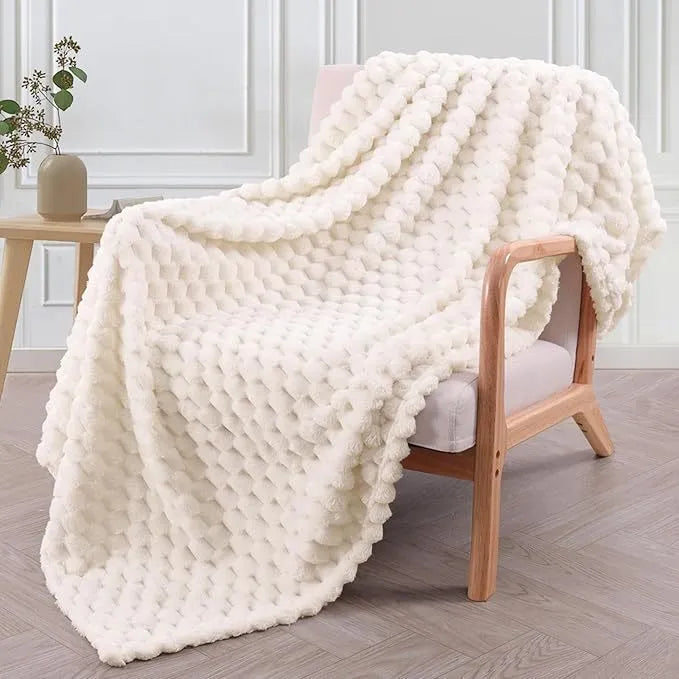 Soft camel-coloured plaid fleece blanket for children folded on a bed.