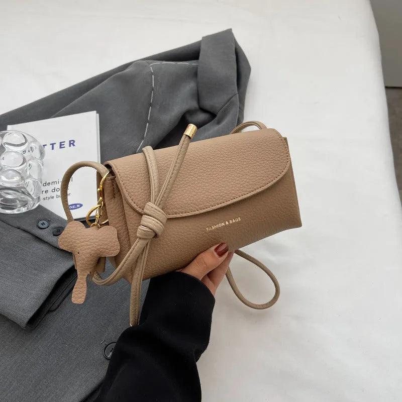 Soft PU small shoulder bag in khaki with pillow silhouette and sewing thread detail, 21cm wide.