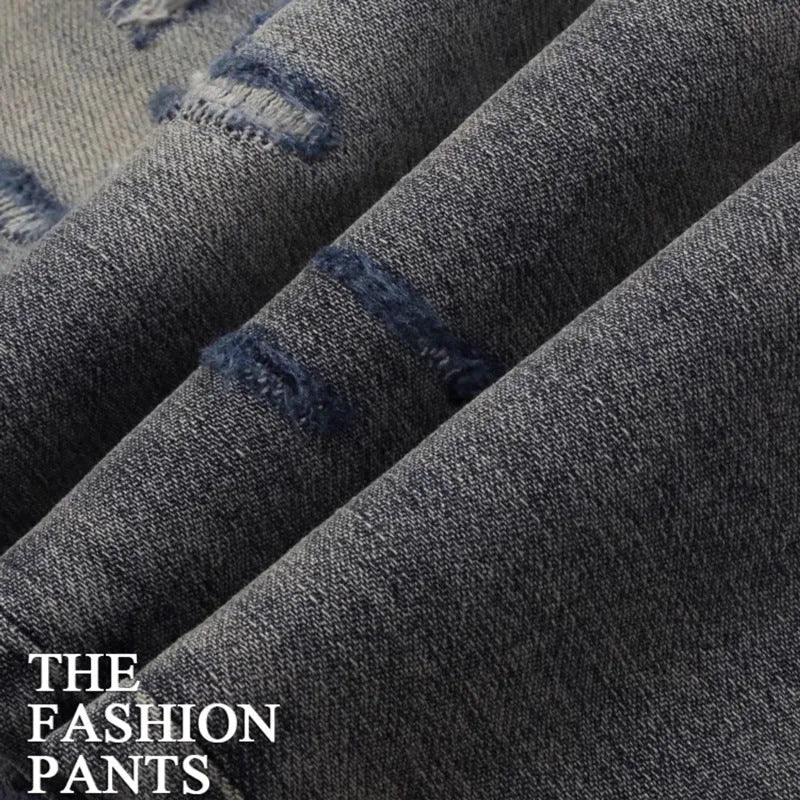Men's old colour slim fit jeans with worn-out patches, holes, and embroidery on the legs.
