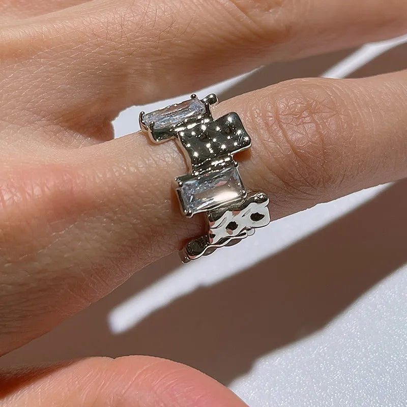 Silver geometric open ring with cross design and zircon decoration on white background