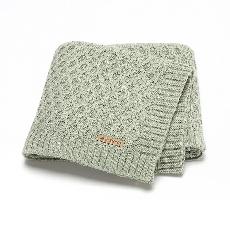 Solid colour infant blanket with textured lines, shown in a choice of colours including pink and beige.