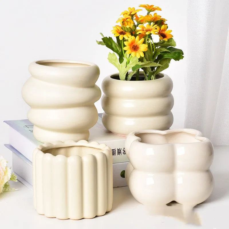Matte yellow ceramic flower pot with a Roman column design on a table.