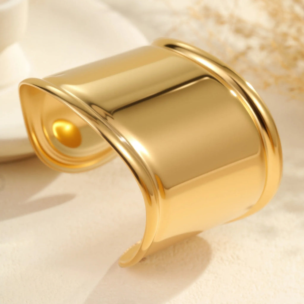 Gold plated wide stainless steel bracelet with a geometric wave shape and a niche opening.