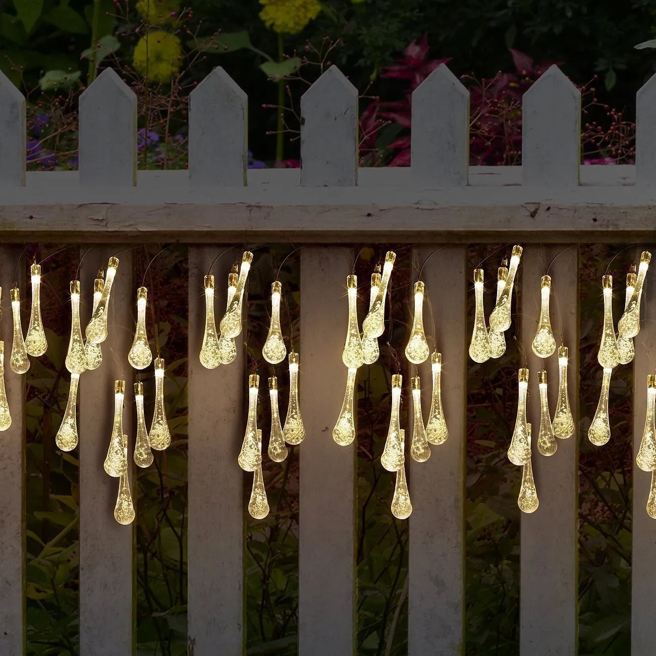 Solar-powered LED outdoor string lights with water drop-shaped pendants in garden setting