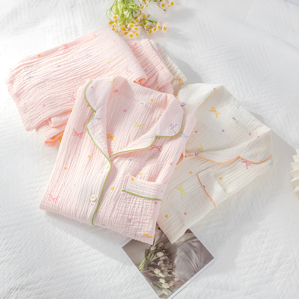 Women's pink cotton long-sleeve pajama top and trousers set laid flat.