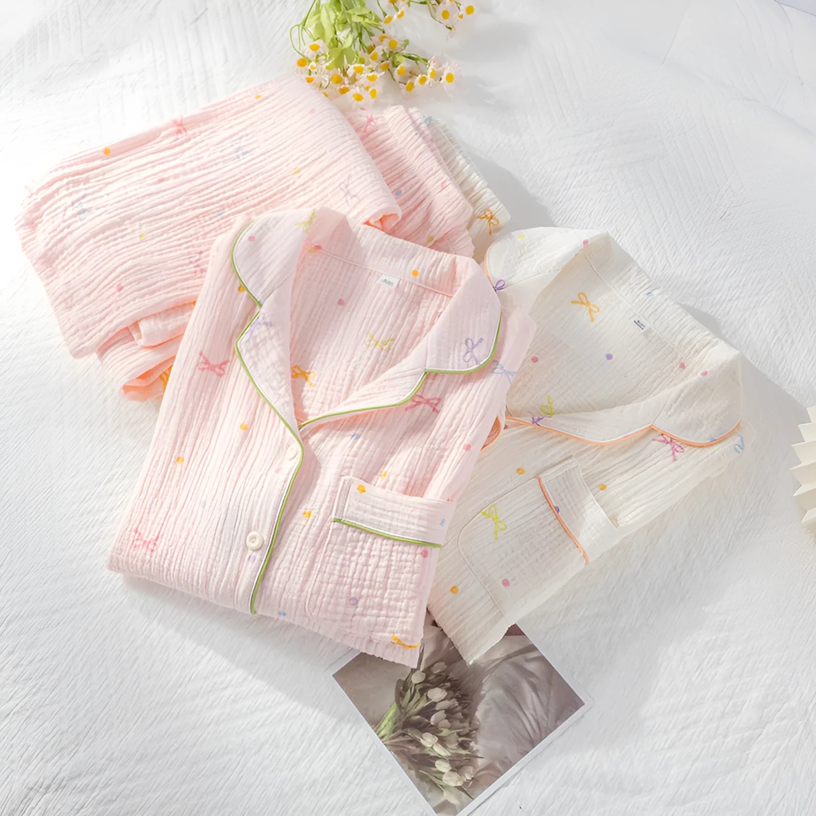 Women's pink cotton long-sleeve pajama top and trousers set laid flat.