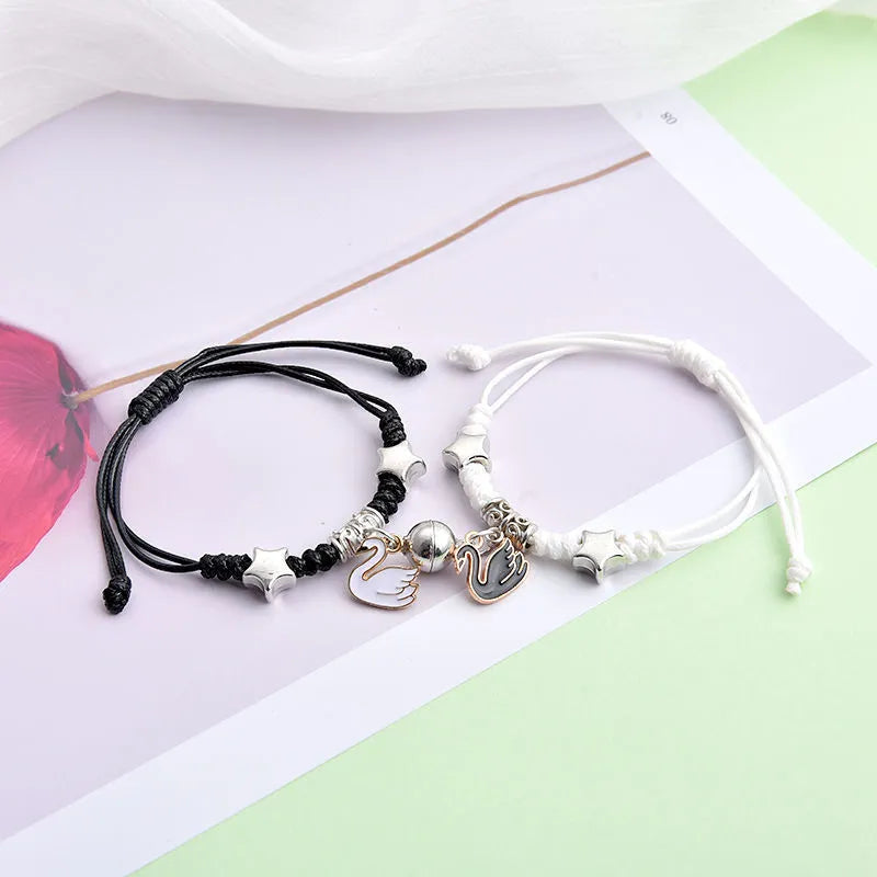 Pair of magnetic suction bracelets with alloy charms in various love and friendship themed designs on a wrist.