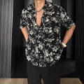 Man wearing a loose black floral print casual short sleeve shirt.