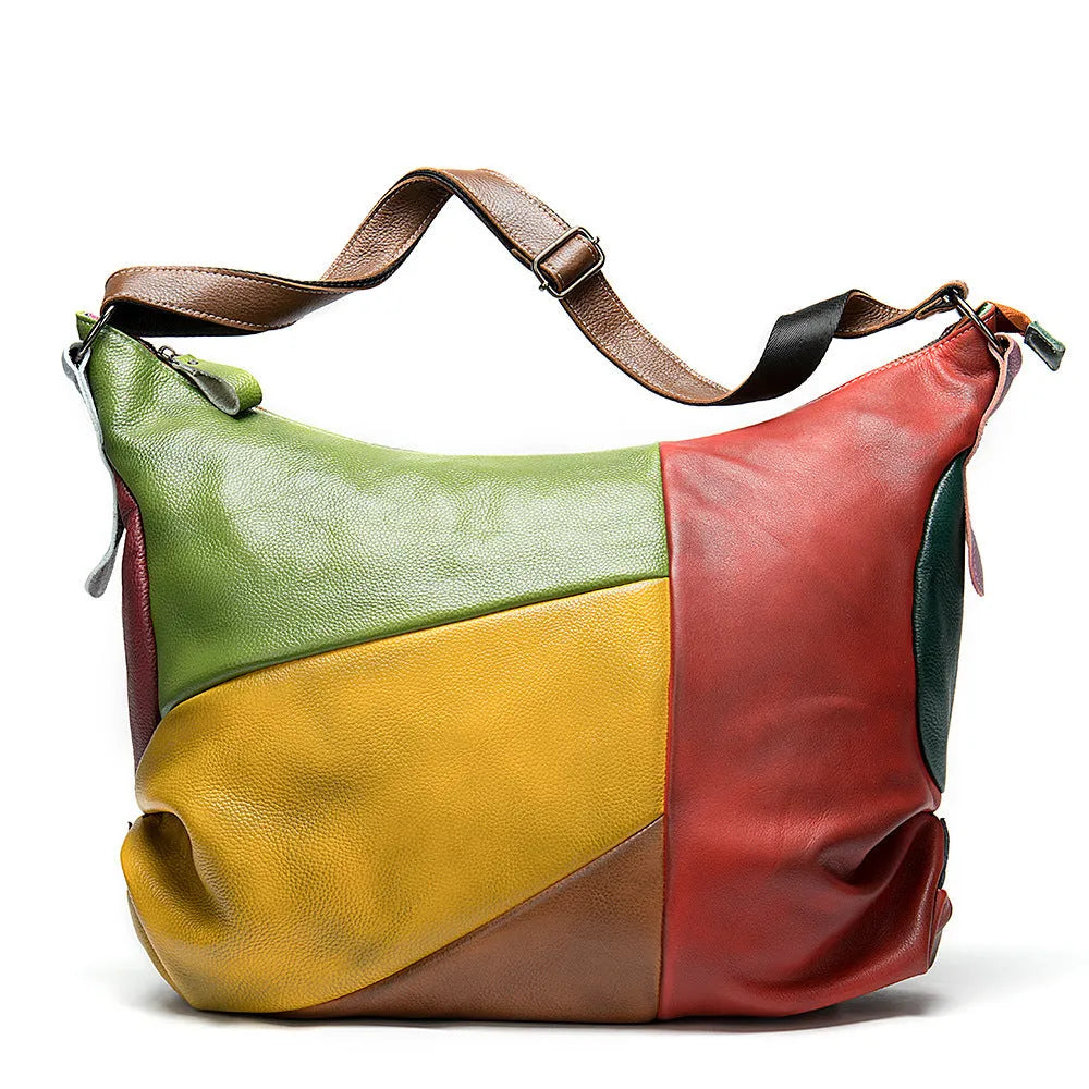 Brown cowhide leather travel bag with stitching details, shown as a crossbody bag holding a laptop.