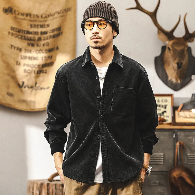 Man wearing a loose-fit black corduroy shirt jacket with long sleeves.