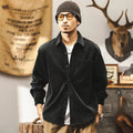 Man wearing a loose-fit black corduroy shirt jacket with long sleeves.