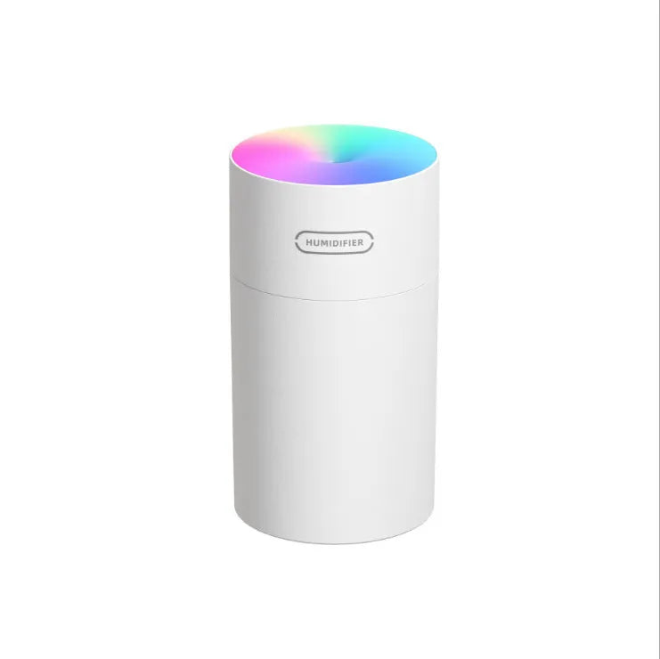 Pink USB desktop humidifier with LED lights and water tank on a wooden desk.