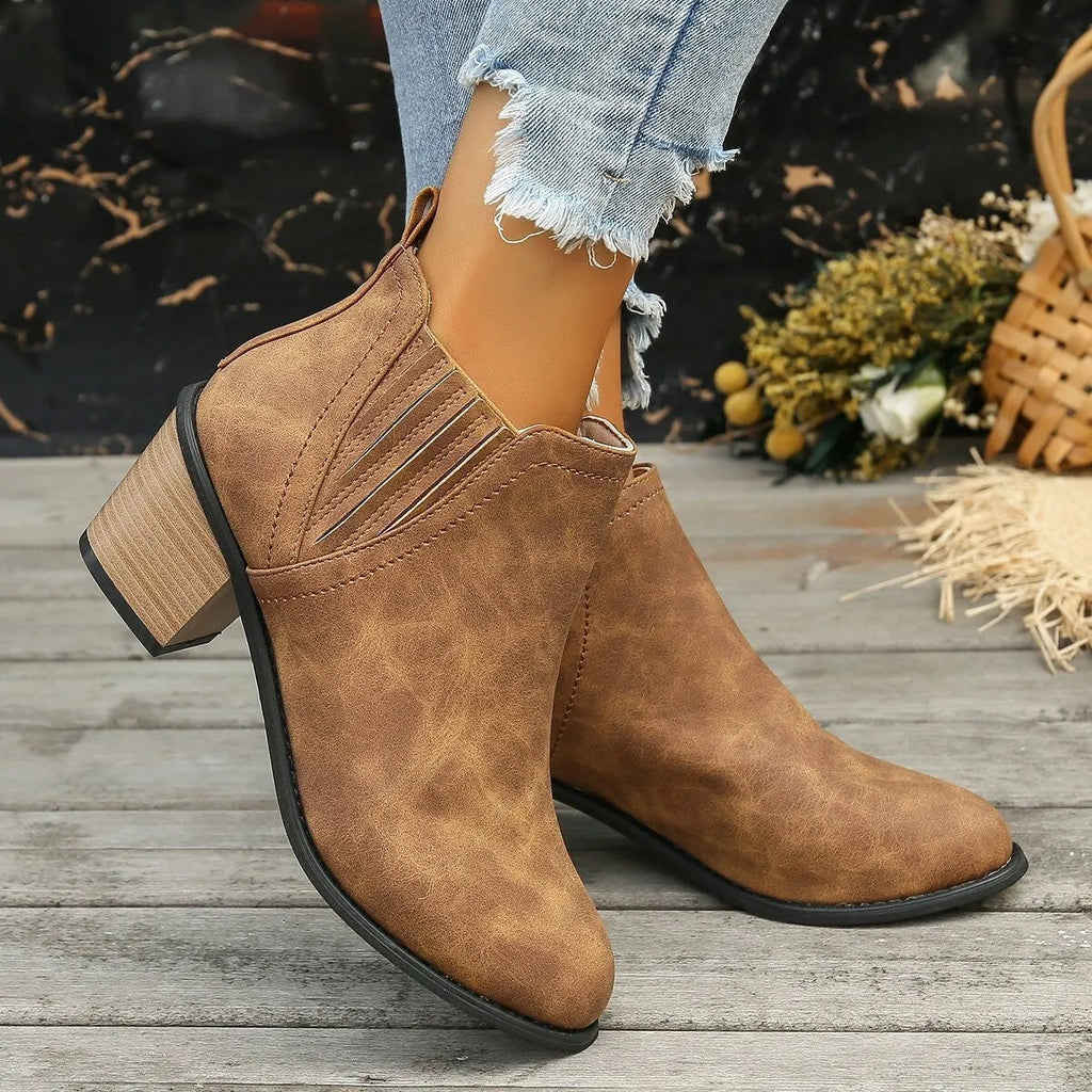 Women's black ankle boots with pointed toe and thick square heel on wooden floor