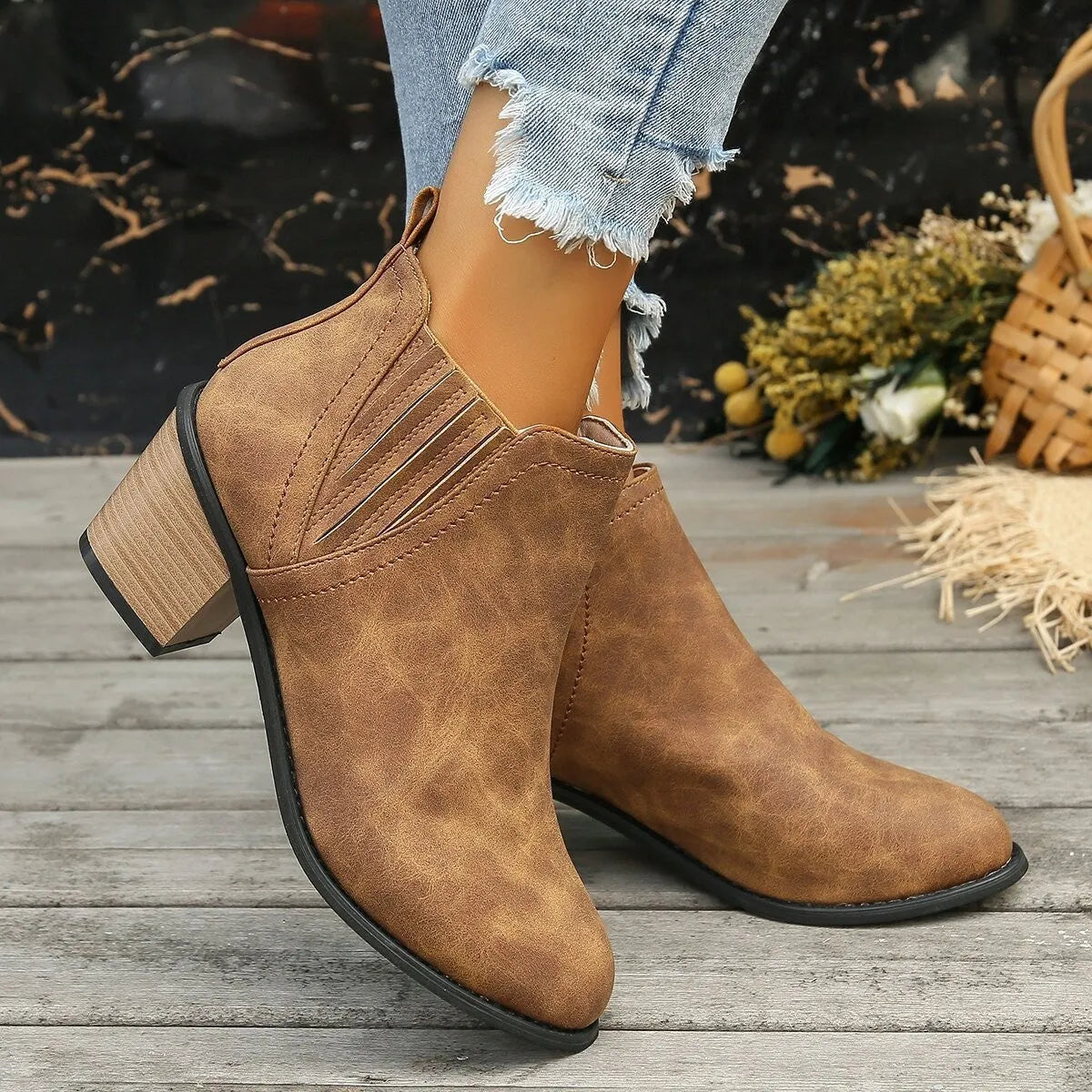 Women's black ankle boots with pointed toe and thick square heel on wooden floor