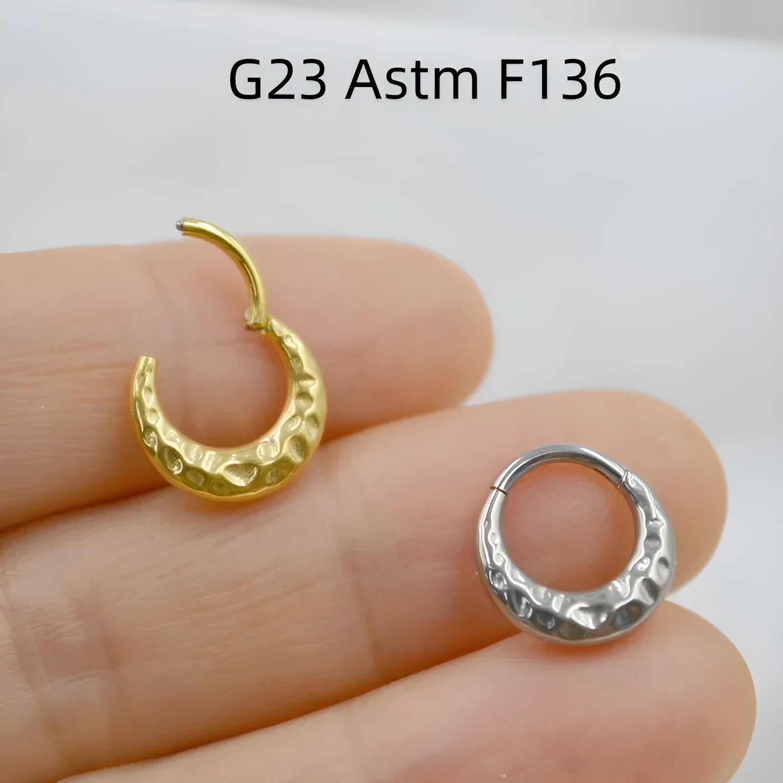 Close-up of a titanium concave-convex nose ring in gold finish, showing its textured profile and 1.2mm thickness.