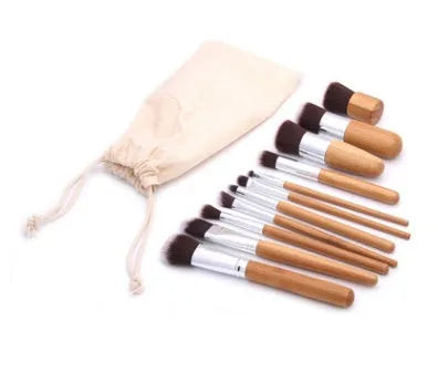 11 bamboo handle makeup brushes arranged on linen bag, including foundation blush and eye shadow brushes