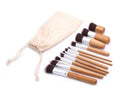 11 bamboo handle makeup brushes arranged on linen bag, including foundation blush and eye shadow brushes