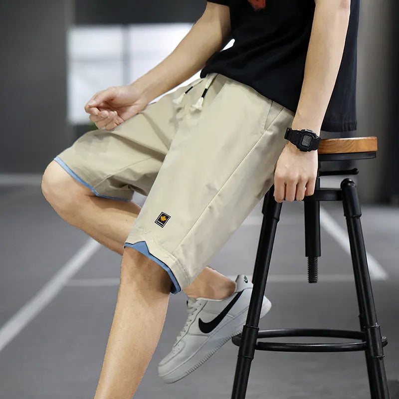 Man modelling loose-fitting straight-leg casual shorts in a solid colour on a beach.