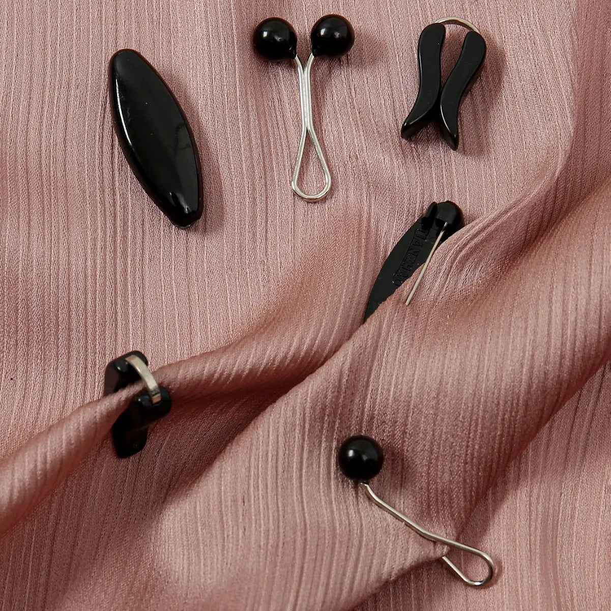 Plastic scarf clip with oval meander pattern and resin drip finish in five colours including black, gray, white, brown, and pink.
