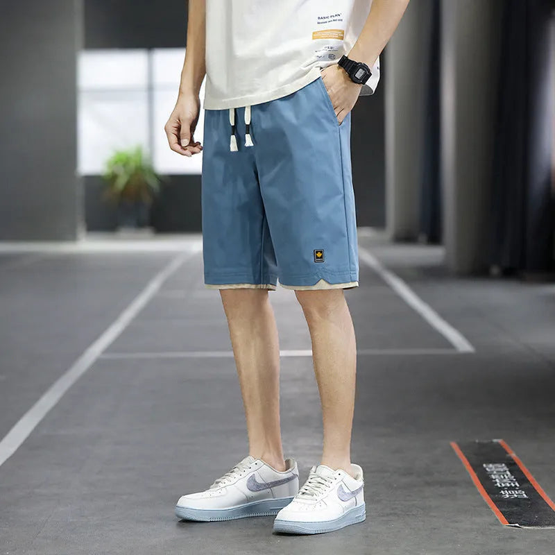 Man modelling loose-fitting straight-leg casual shorts in a solid colour on a beach.