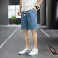 Man modelling loose-fitting straight-leg casual shorts in a solid colour on a beach.