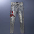 Men's old colour slim fit jeans with worn-out patches, holes, and embroidery on the legs.
