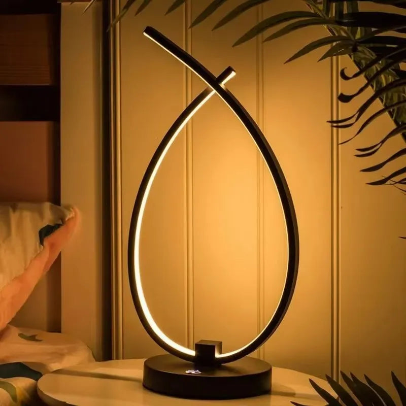 Black and white drop-shaped USB table lamp on a wooden desk.