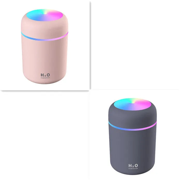 Pink USB desktop humidifier with LED lights and water tank on a wooden desk.