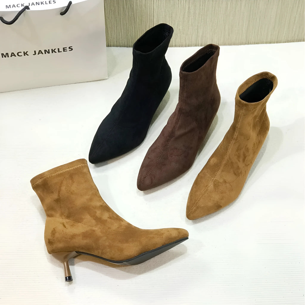 Black pointed toe women's ankle boots with stiletto heels on a neutral background.