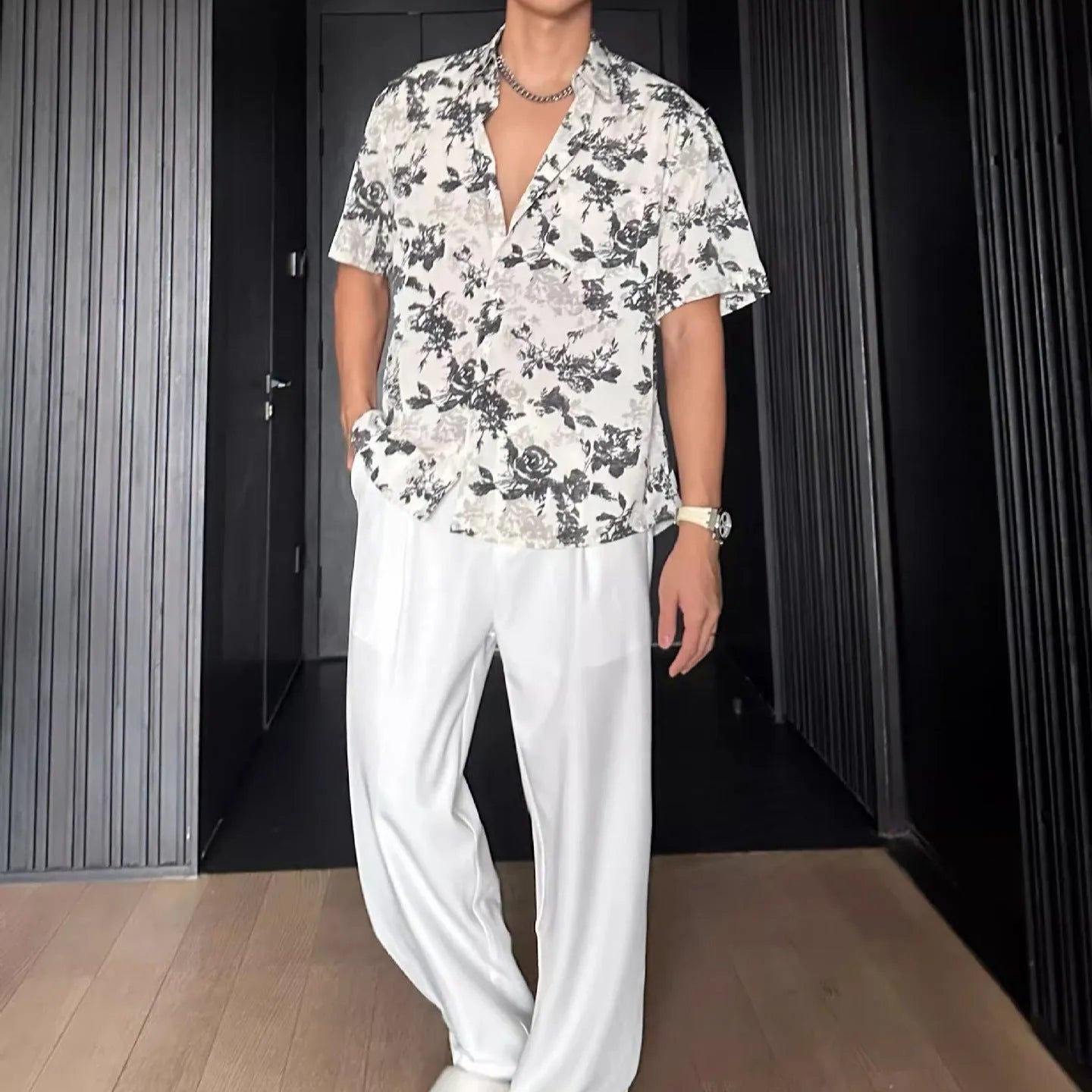 Man wearing a loose black floral print casual short sleeve shirt.