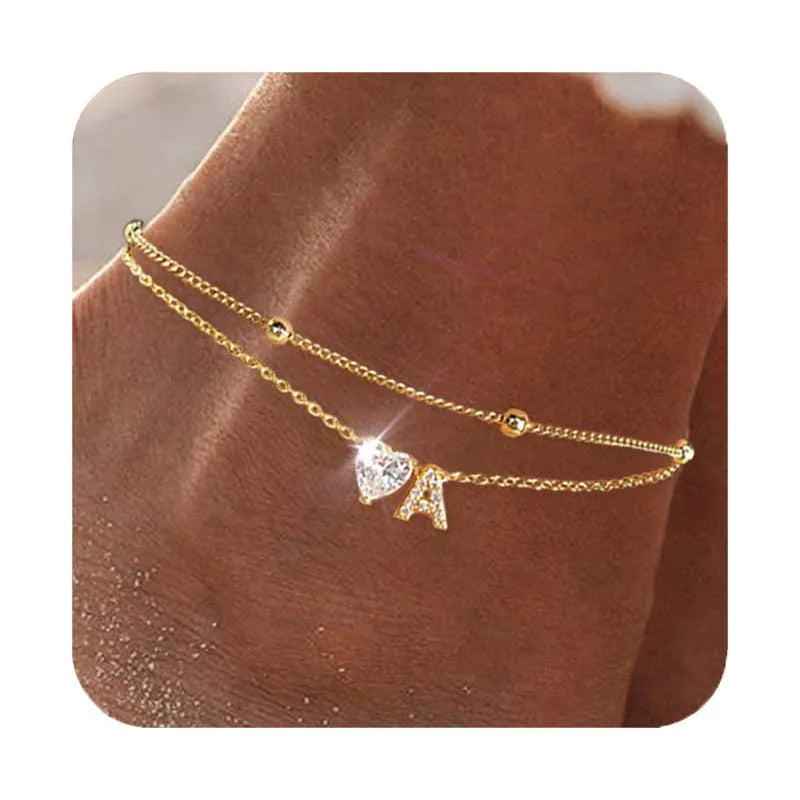 Layered copper anklet with zircon inlaid letter charm, bead zircon style, on a light background.