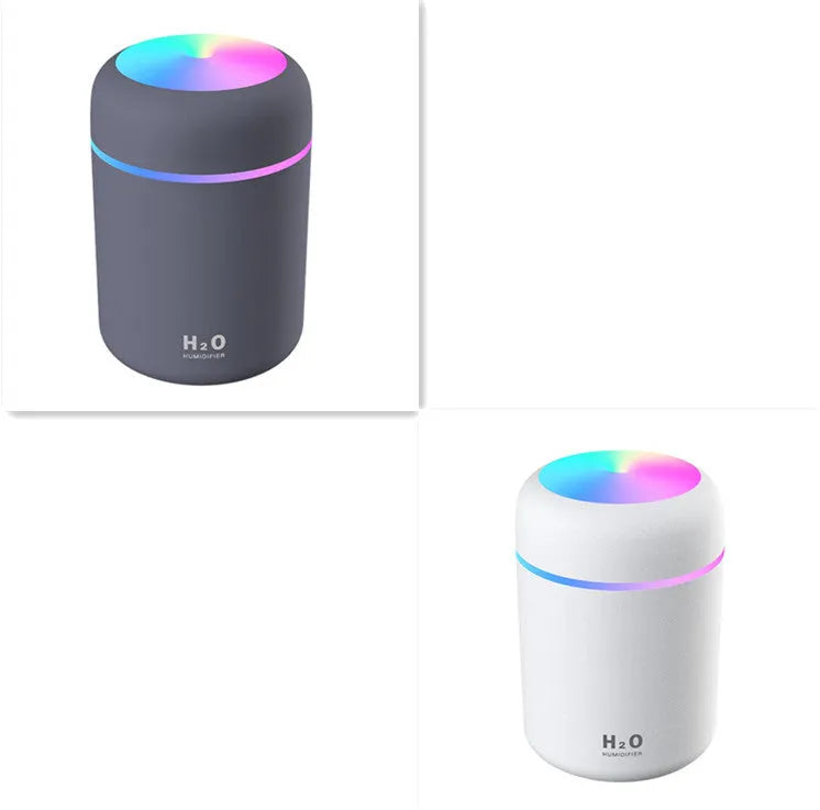 Pink USB desktop humidifier with LED lights and water tank on a wooden desk.