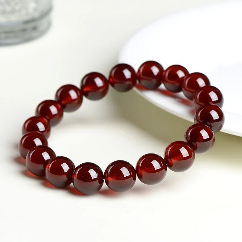 Natural orange red garnet ball bracelet in retro unisex style on wrist, showing crystal links and ruyi design details.