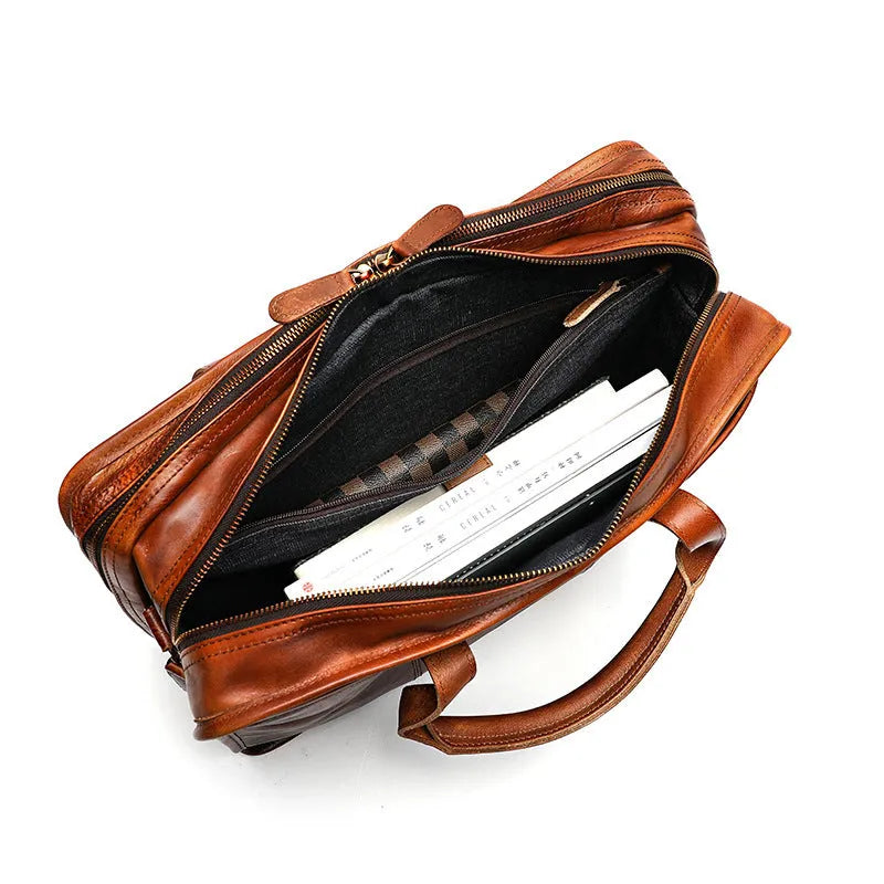 Black vintage leather men's briefcase open to show internal laptop pocket, camera pocket, and document organisation.