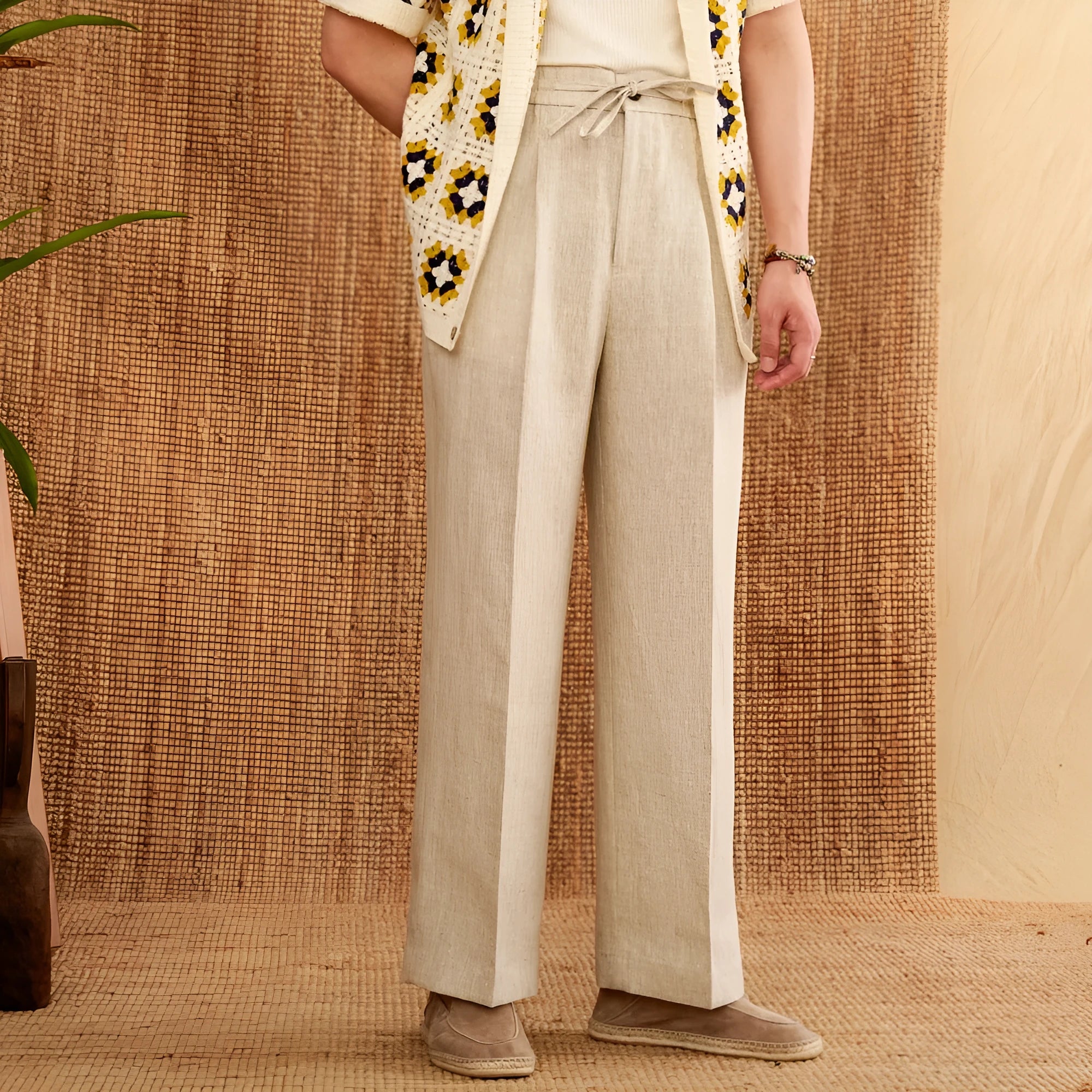 A pair of loose-fit, high-waisted linen trousers in a neutral colour with an elasticated waistband and straight legs.