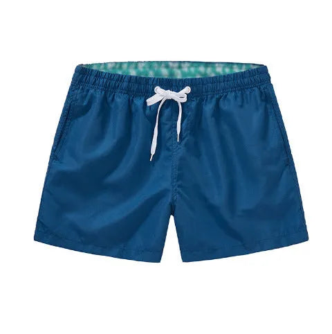 Men's black surf shorts made from polyester fabric with a straight leg opening, shown on a size chart.