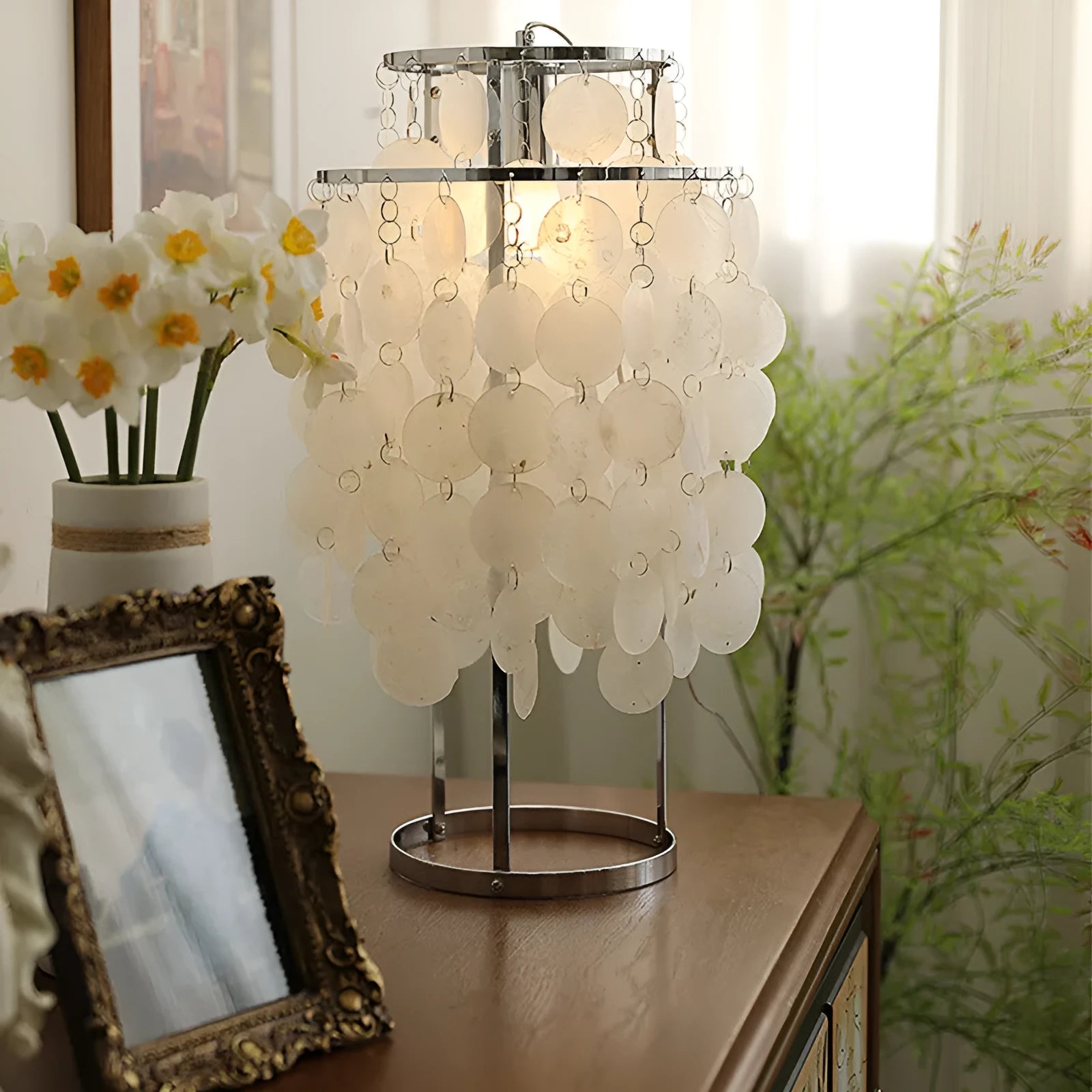 Creative modern shell-shaped table lamp in chrome or gold finish on a bedside table.