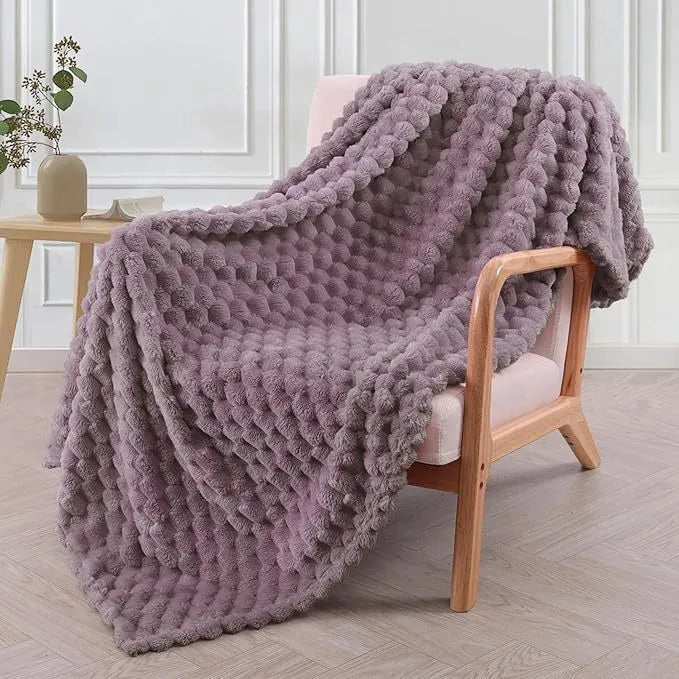 Soft camel-coloured plaid fleece blanket for children folded on a bed.